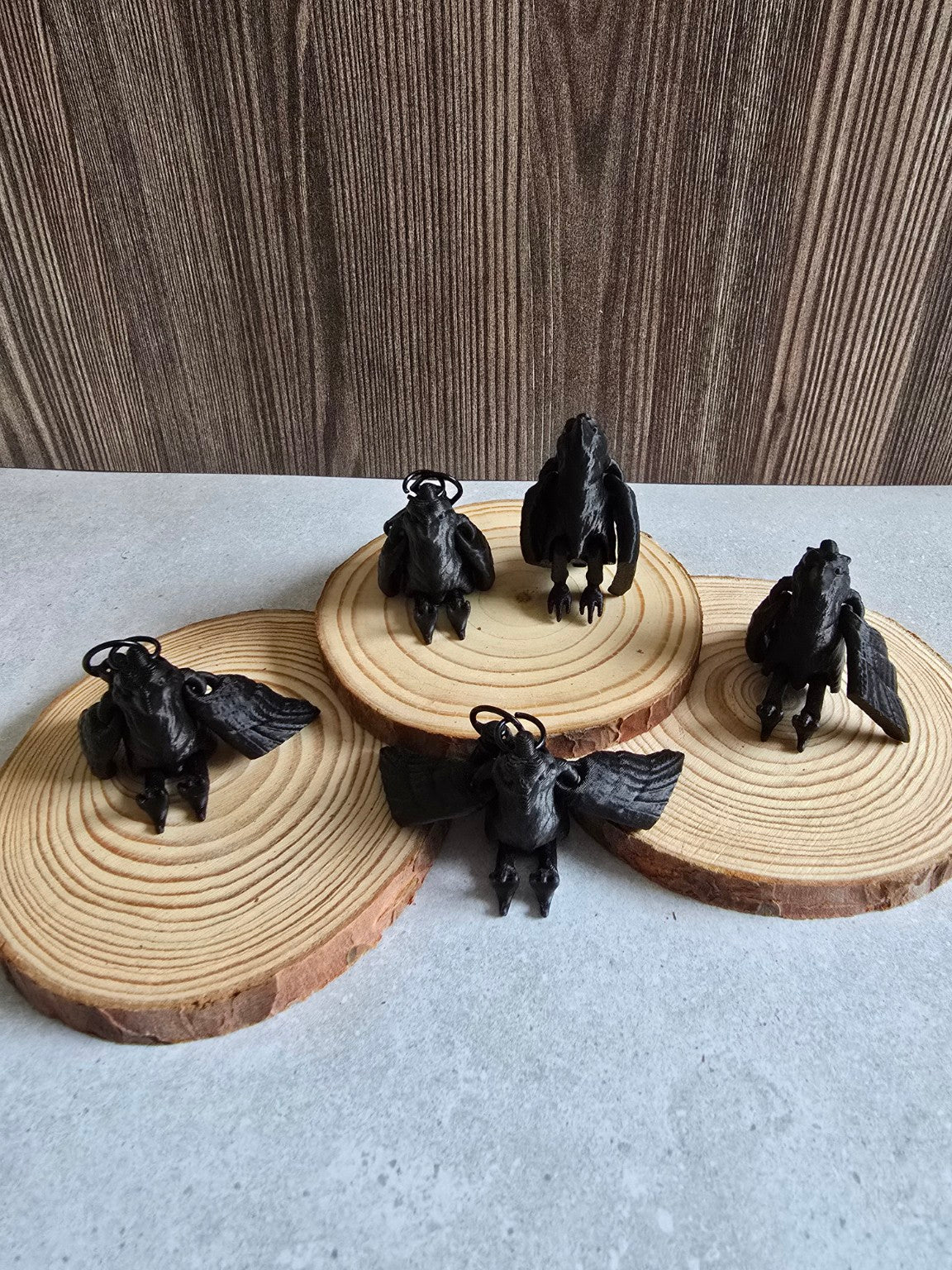 Five black raven keychains on wood slices
