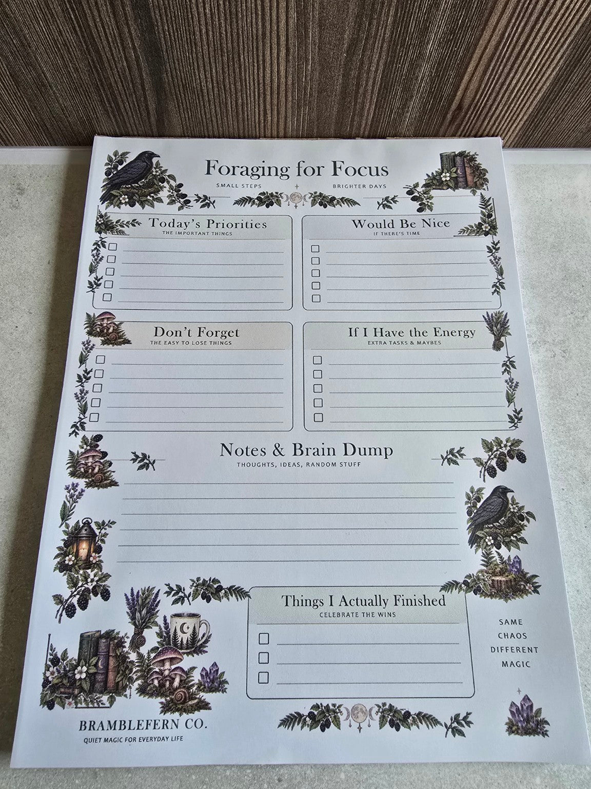 Angled photo of Bramblefern Foraging for Focus notepad with woodland botanical illustration and six planning sections