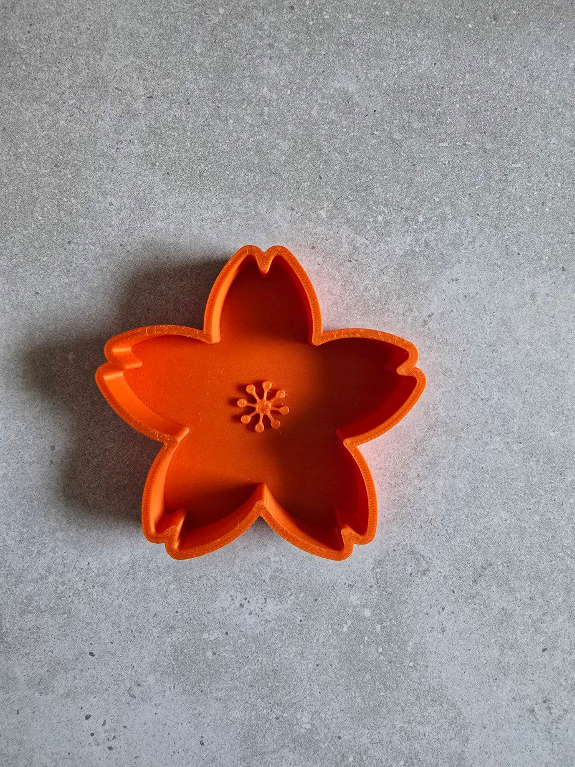 Orange five-petal 3D printed cherry blossom trinket dish, empty.