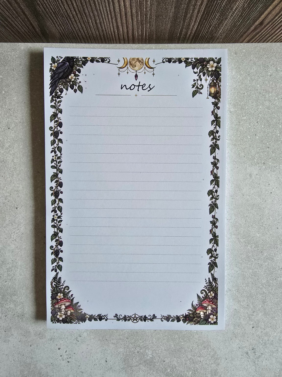 Moonlit Woodland Notes gothic lined notepad, front view with triple moon, raven, vines, mushrooms and lantern
