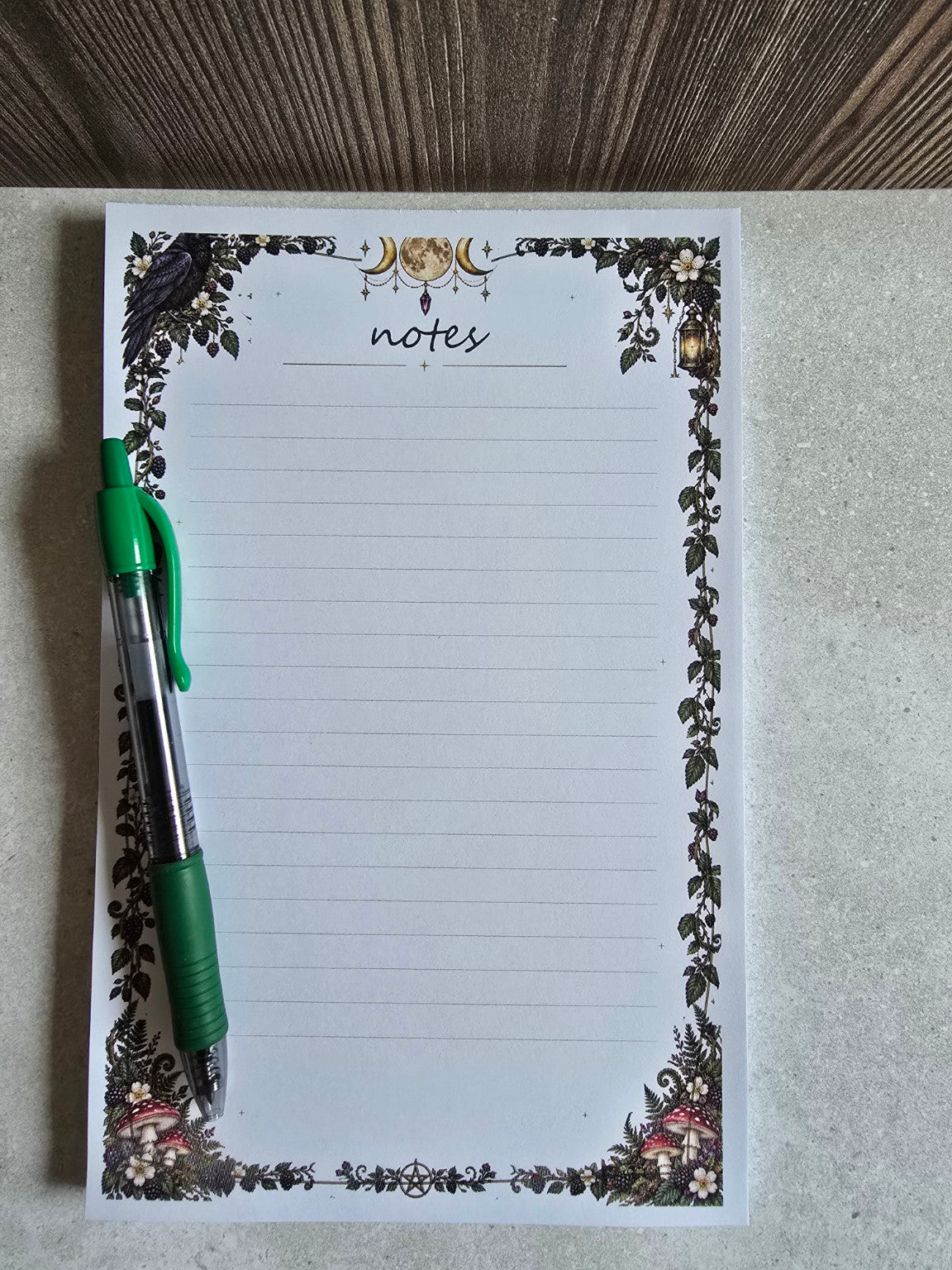 Moonlit Woodland Notes half-page lined notepad next to a green pen for scale