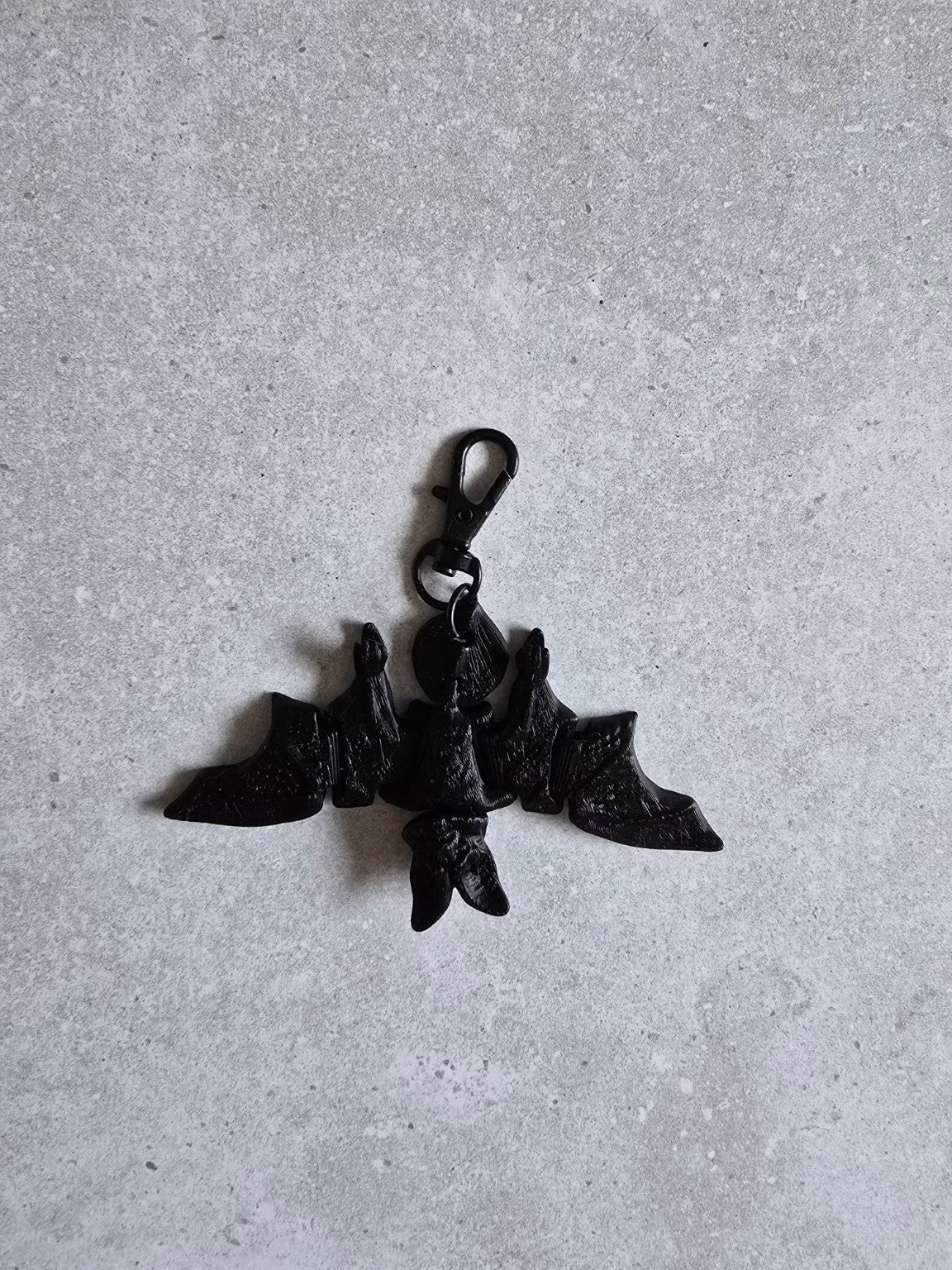 Black articulated bat keychain flat lay