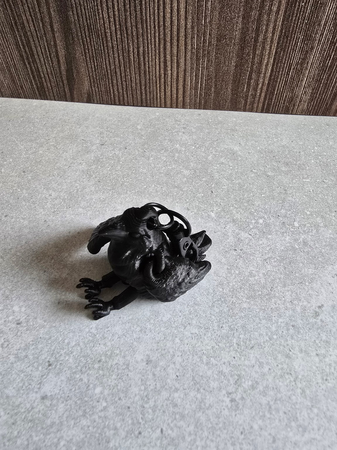 Black raven keychain resting on gray surface