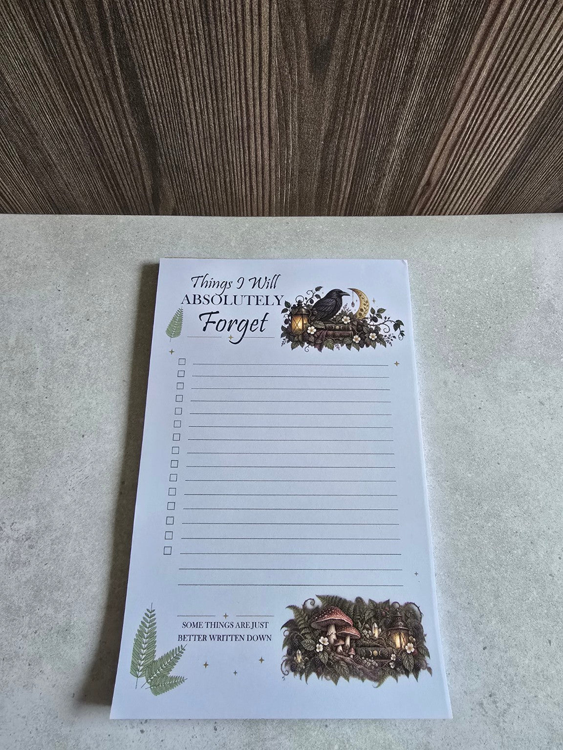 Angled view of Bramblefern raven notepad with lined checklist and botanical art