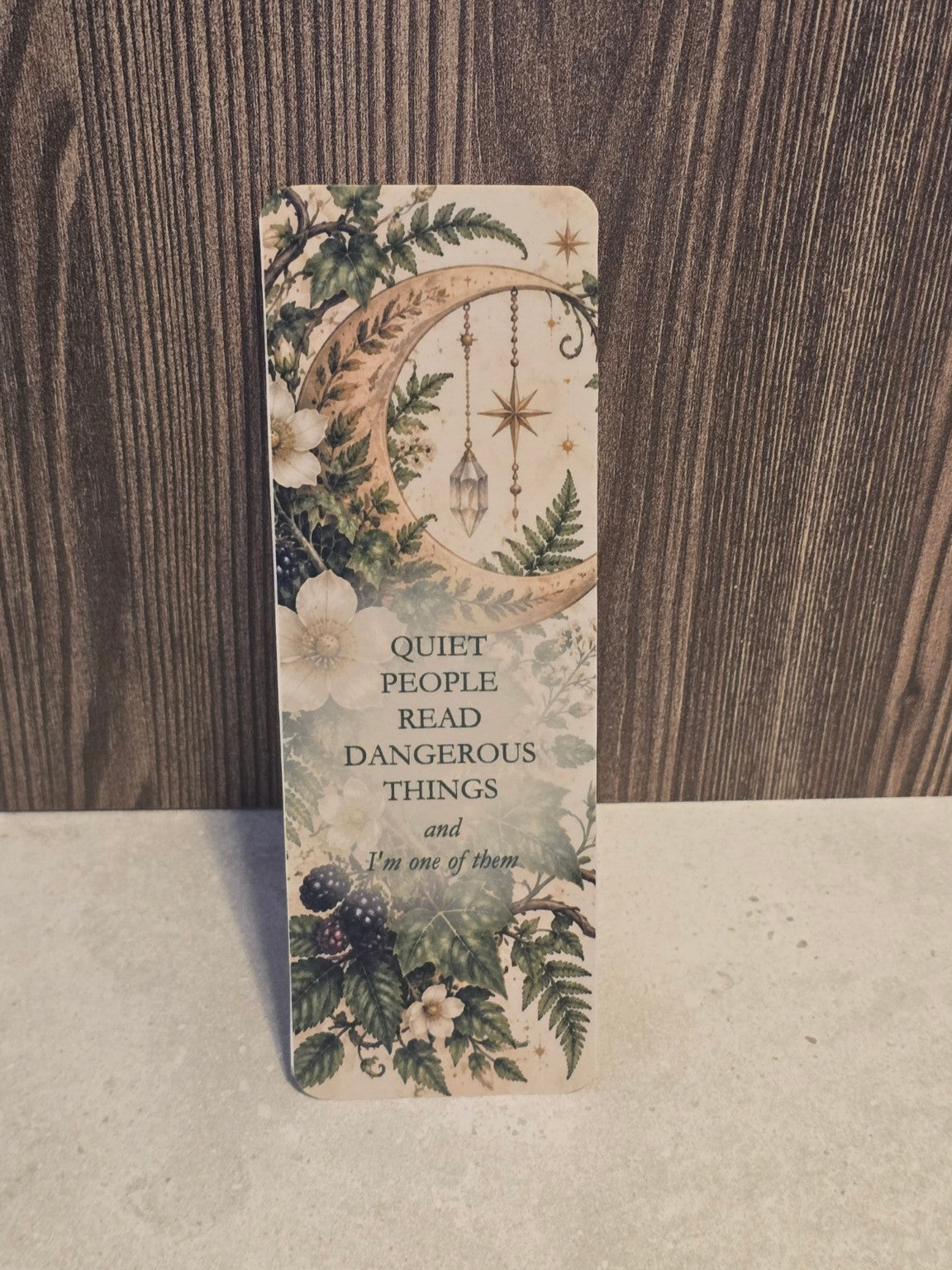 Quiet People Read Dangerous Things laminated bookmark with a golden crescent moon, hanging crystals and blackberry vines.
