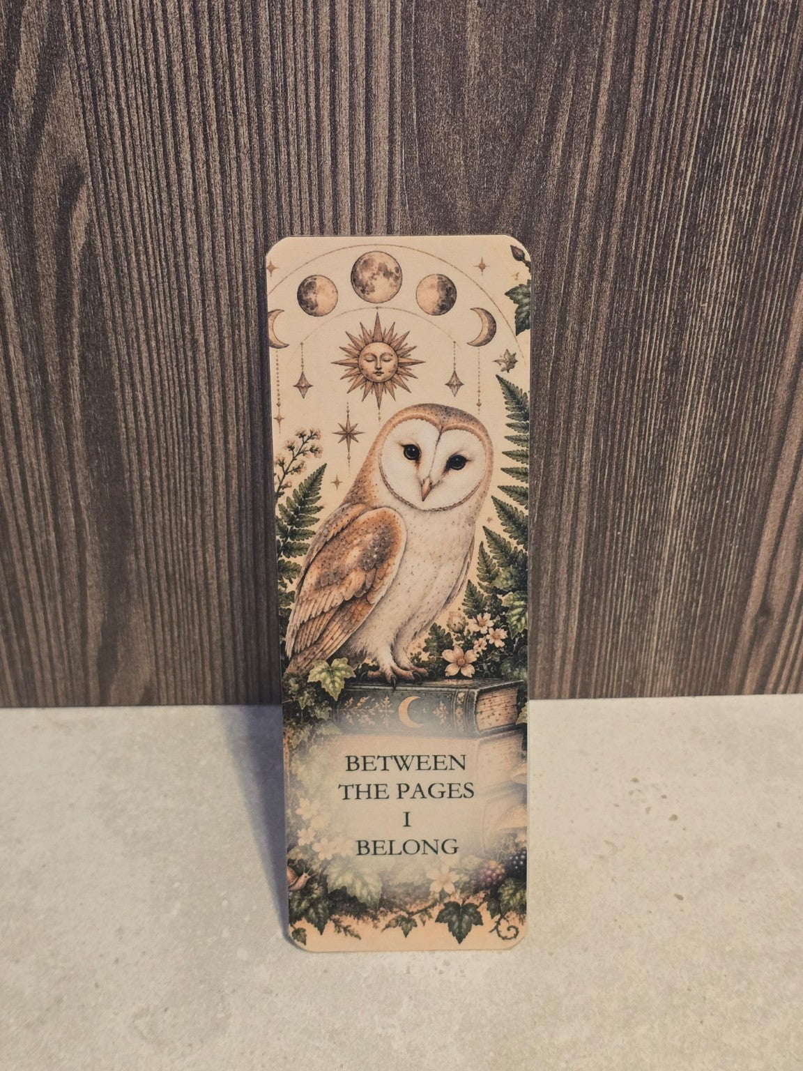 Between the Pages I Belong laminated bookmark showing a barn owl perched on a book beneath moon phases.