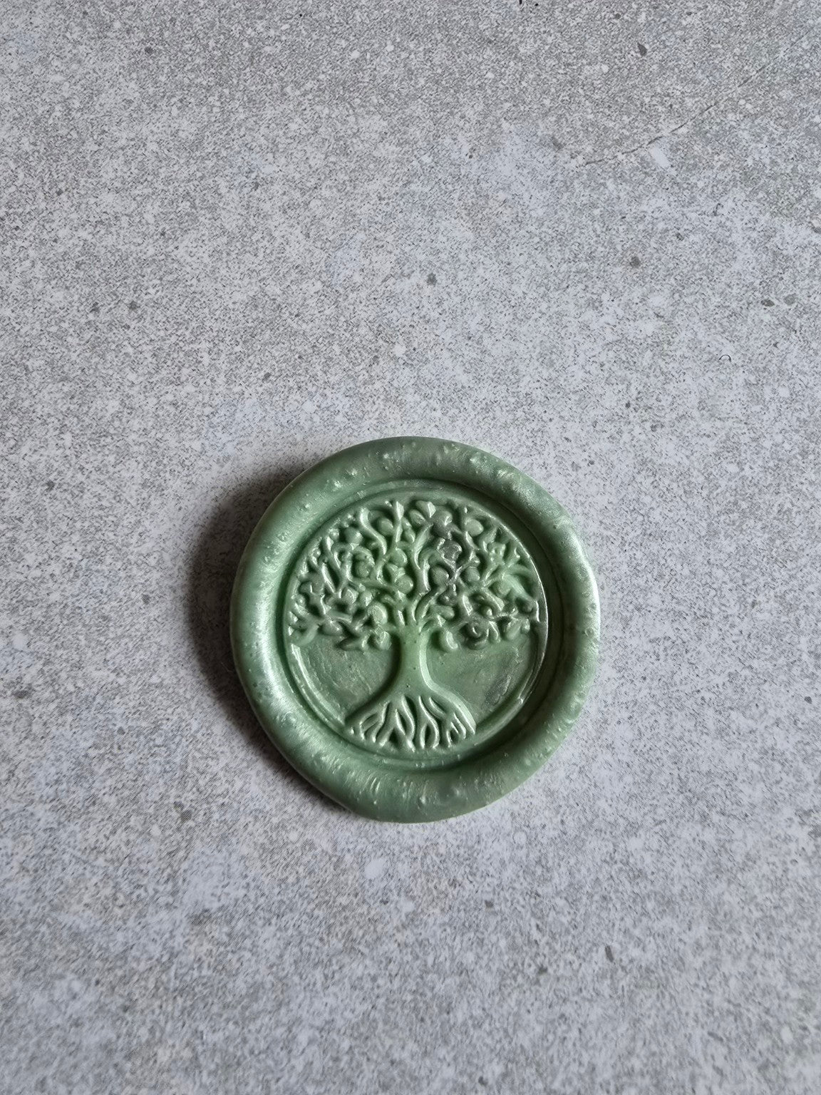 Close-up of a handmade Tree of Life wax seal with raised tree design.