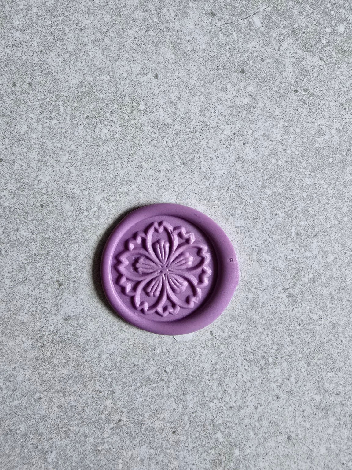 Close-up of a handmade wax seal with an embossed floral mandala.