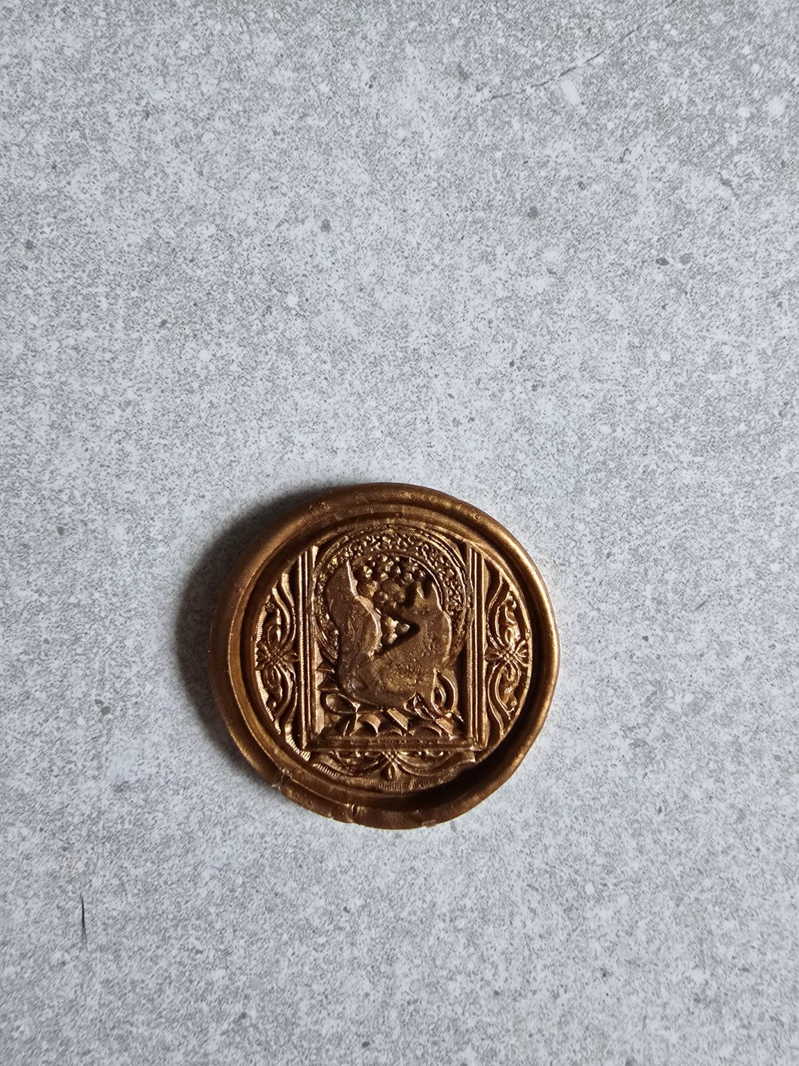 Close-up of a handmade wax seal with an ornate fox design.