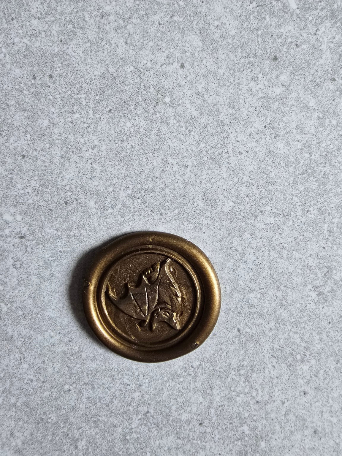 Close-up of a handmade wax seal with an embossed bat design.